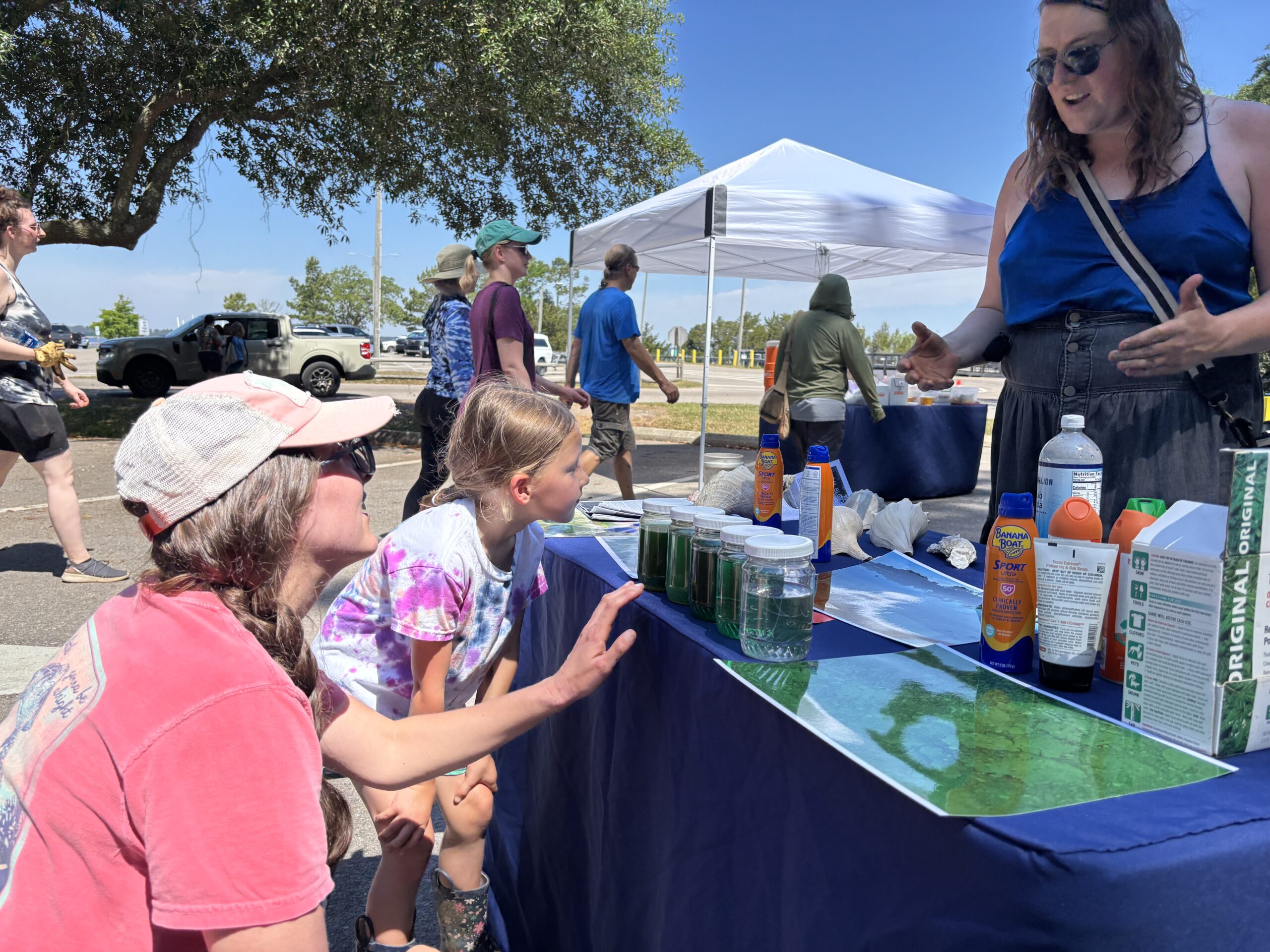 people at an outdoor event looking at display of algae bloom